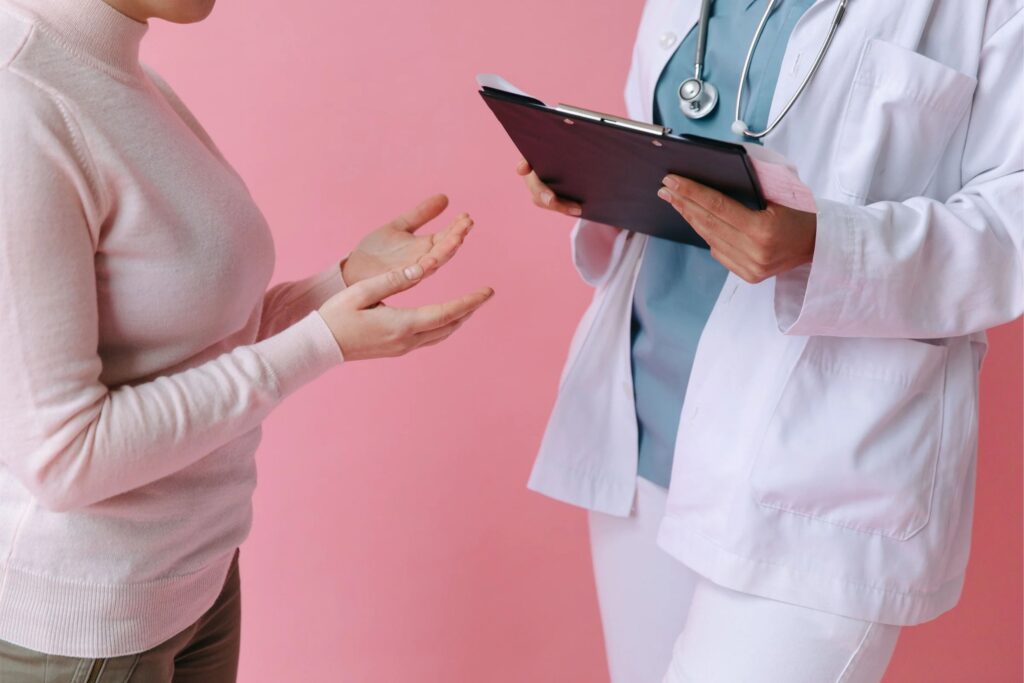 A picture of the torsos of a patient speaking with their doctor, who is holding a clipboard.