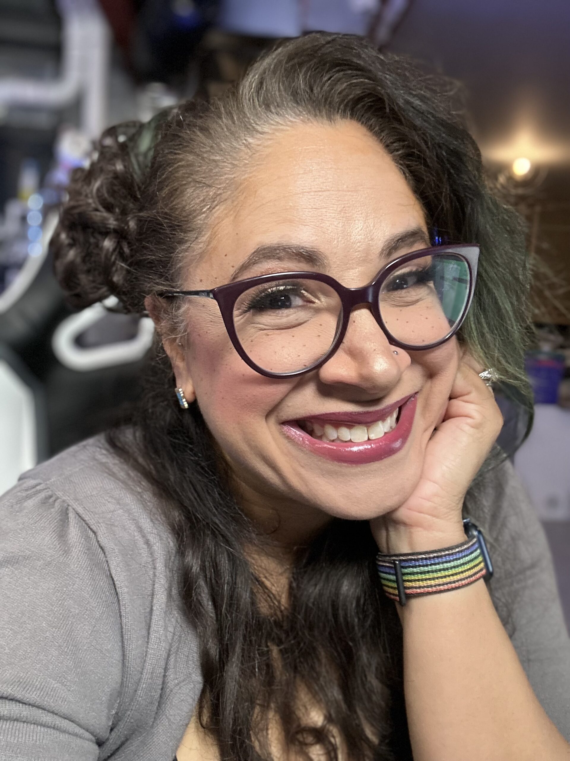 Headshot of a woman wearing glasses, red lipstick and a gray tshirt. She is smiling and looking at the camera.