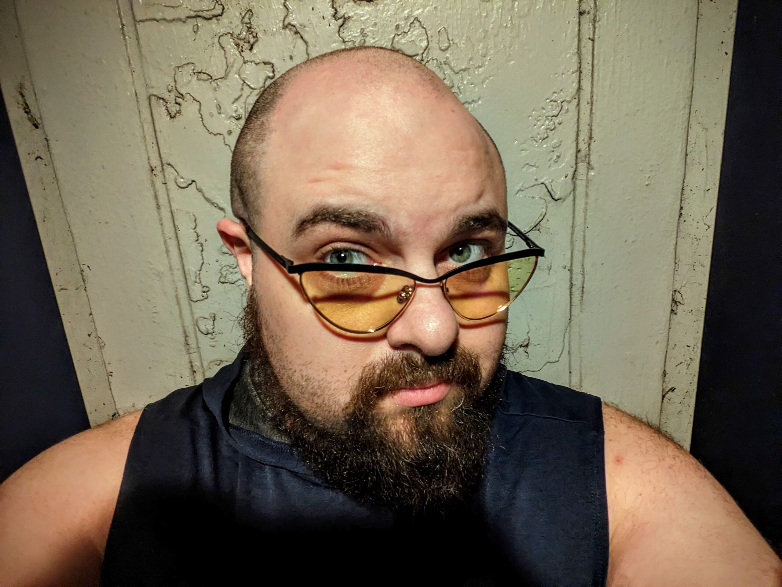 Headshot of a man with a shaved head and goatee and who is wearing orange-tinted glasses