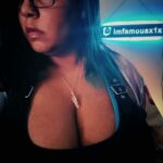Picture of a woman wearing a black tank top, necklace and glasses. Her face is somewhat obscured by the angle of the camera.