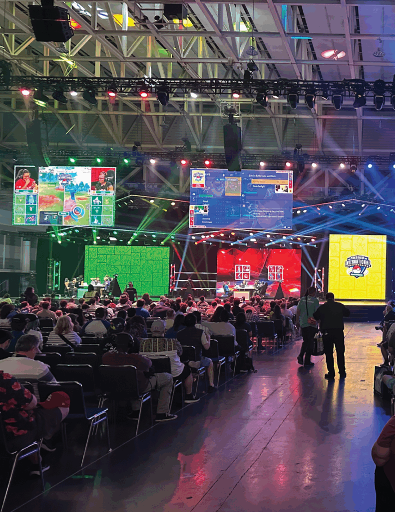 Picture of the pokemon main stage with screens in the background and an audience in the foreground
