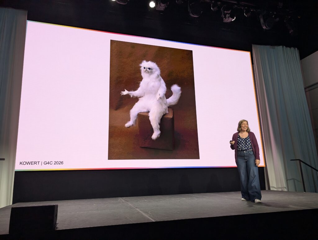 Photo of Dr. Rachel Kowert standing on a stage in front of a projected image of a small white monkey creature shrugging.